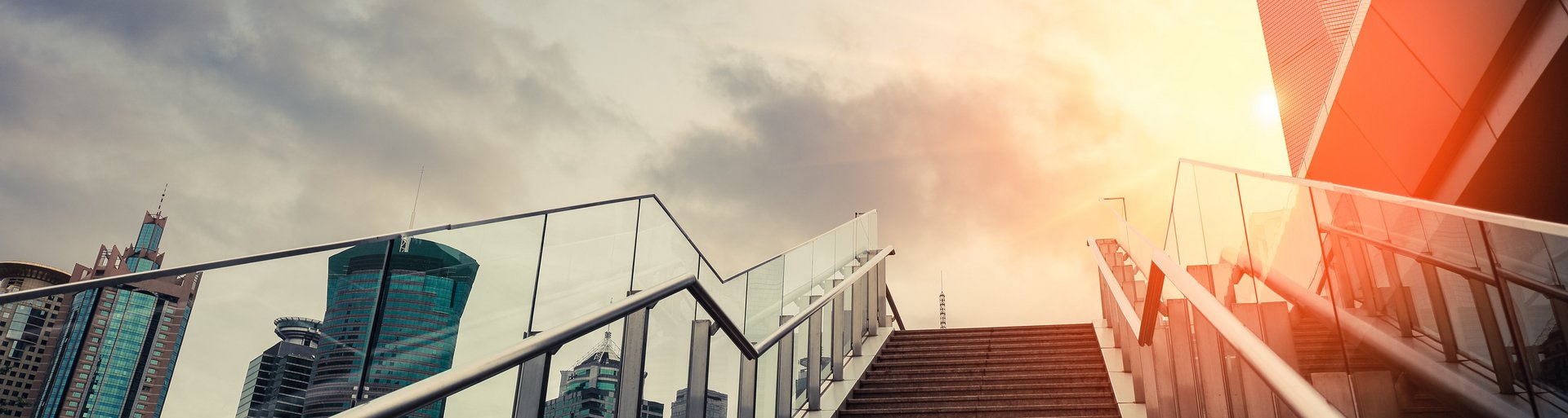 Ansicht einer modernen Glasfassade mit Treppenaufgang, die den Aufstieg symbolisiert. Das Bild vermittelt den Eindruck von Fortschritt und Entwicklung und steht im Kontext der M2-Philosophie zu Kunden und Partnerschaften.